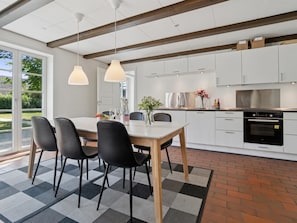 Eine moderne Küche mit weißen Schränken, einem Edelstahlbackofen und einem Essbereich mit Tisch und Stühlen.