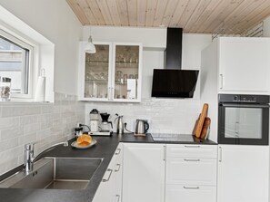 Een moderne keuken met een RVS spoelbak, een koffiezetapparaat, een waterkoker en een inbouwoven.