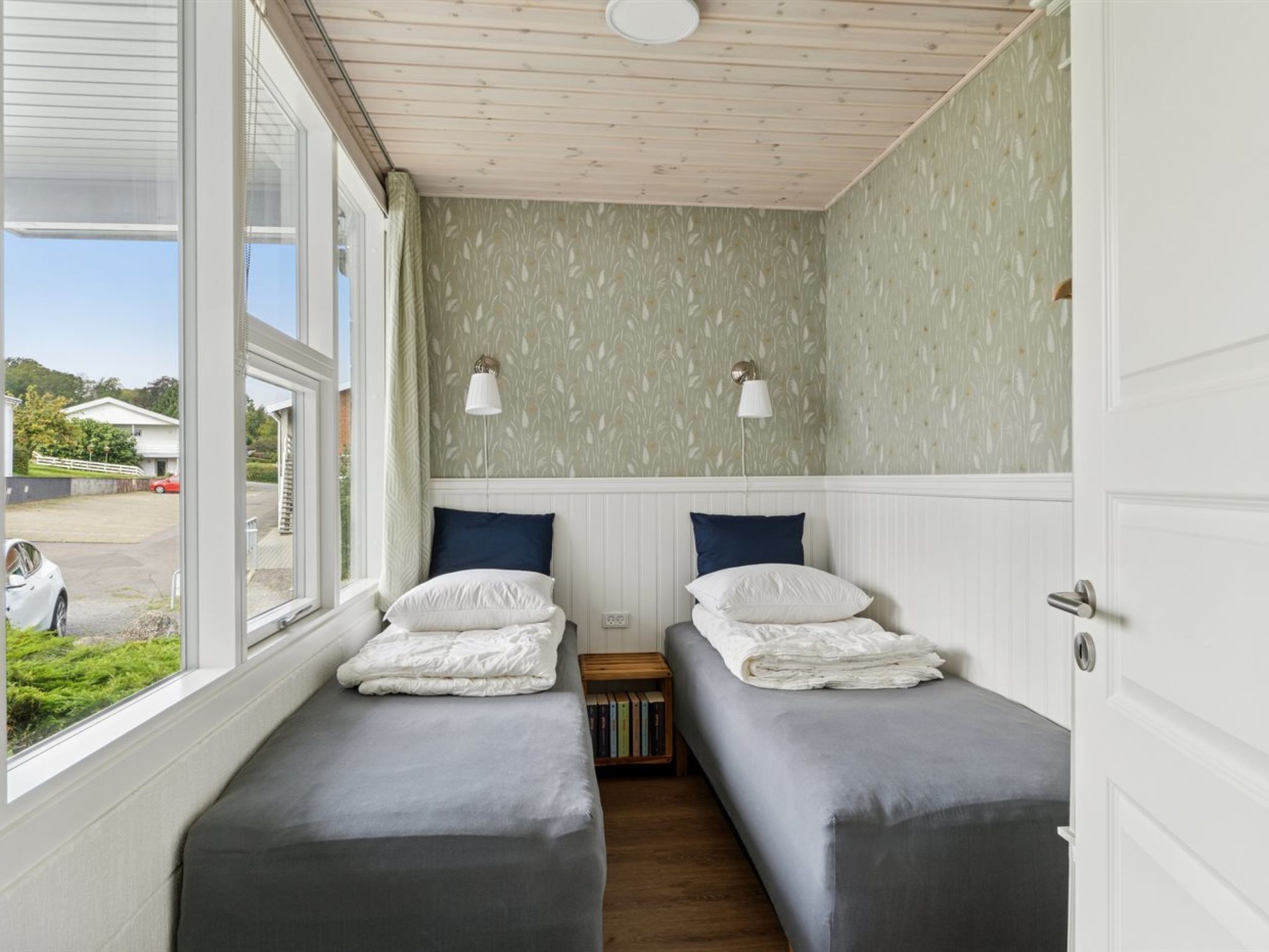 Een kamer met twee bedden, een raam en uitzicht op buiten.