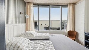 Une chambre avec deux lits, une fenêtre, une chaise et un bureau.