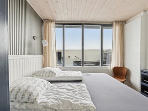 Ein Schlafzimmer mit zwei Betten, einem Fenster, einem Stuhl und einem Schreibtisch.