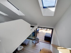 Ein modernes Interieur mit einer Treppe, einer Sitzecke mit Tisch und Blick durch eine Glastür auf eine Terrassenförmige Anlage.