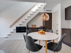 Eine moderne Küche mit Essbereich, einer Treppe und einem Fernseher.