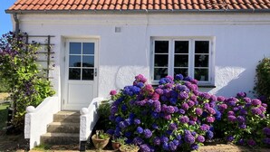 A white building with a red-tiled roof, a white door, and two windows. - "Hening" - 150m from the sea by Interhome (Allinge)