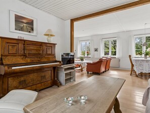 Una sala de estar amplia con un piano de madera, un televisor y un comedor con mesa y sillas.