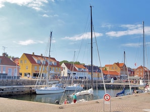 Un puerto deportivo con barcos amarrados, un frente marítimo de arena y edificios coloridos al fondo.