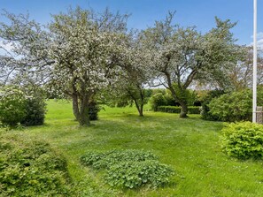 Un jardín con árboles en flor y césped cuidado.