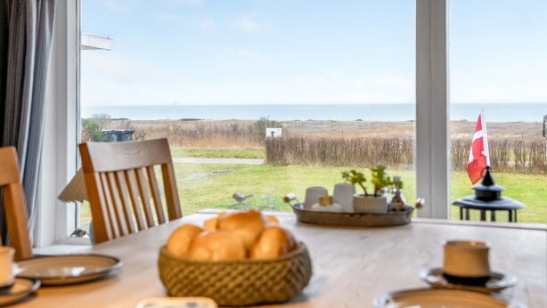 Una mesa de comedor con vistas al mar, una bandera y una cesta de pan.