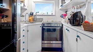 Una cocina moderna con armarios blancos, horno empotrado, microondas y una ventana sobre el lavadero.