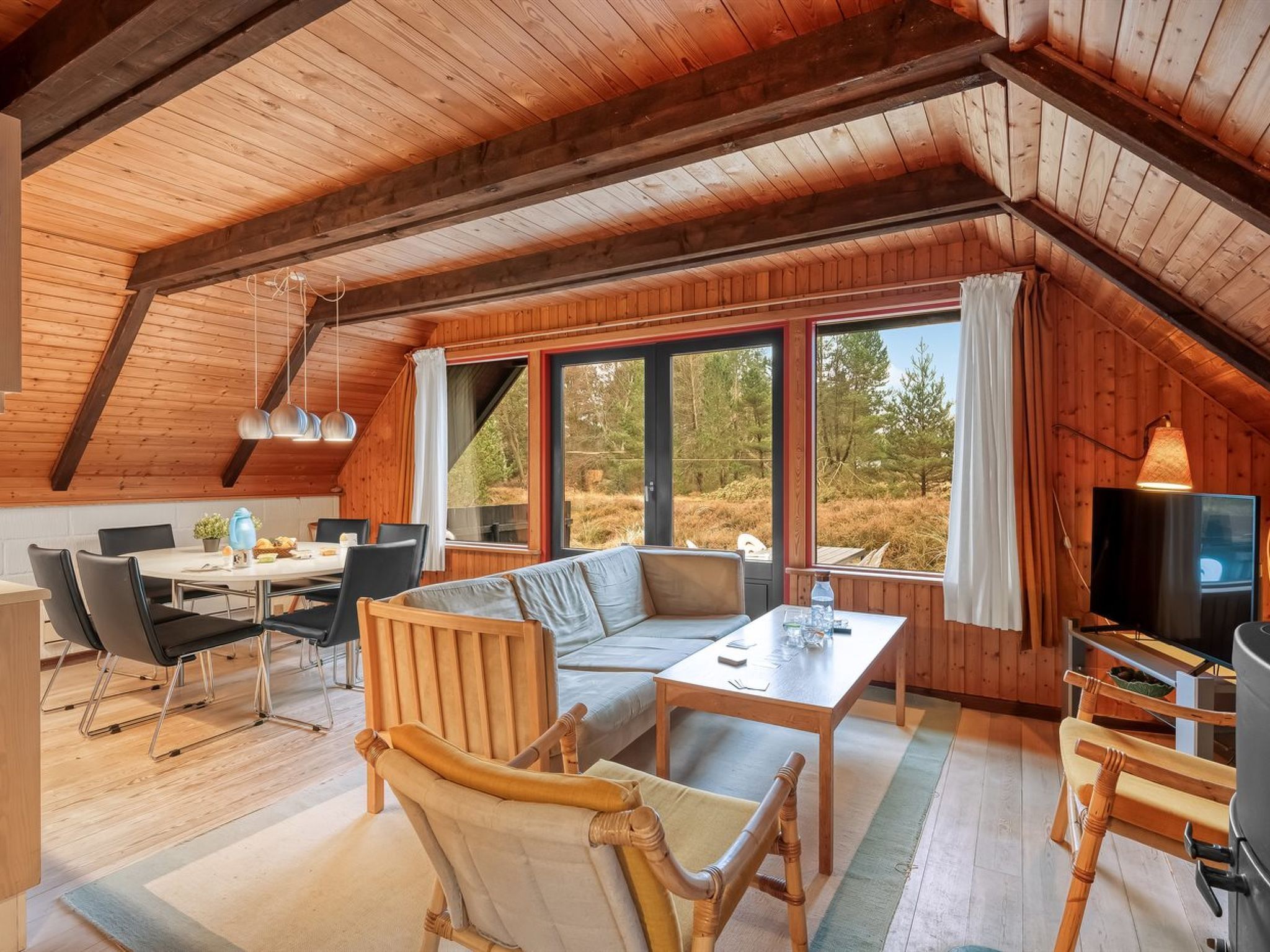 A cozy, wooden interior with a dining area, seating, and a TV.