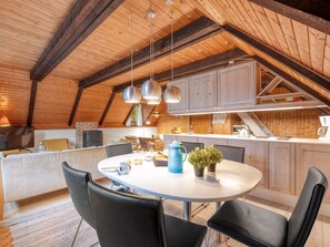 Eine gemütliche Küche mit einem runden Esstisch, schwarzen Stühlen und Holzbalken an der Decke.