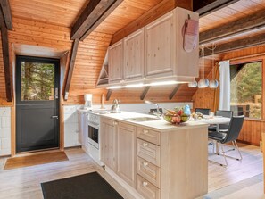 Eine moderne Küche mit Holzschränken, einer zentralen Kochinsel und einem Essbereich mit Tisch und Stühlen.