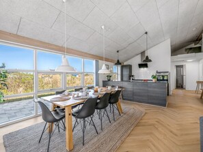 Eine moderne Küche mit Essbereich, großen Fenstern und Blick ins Freie.