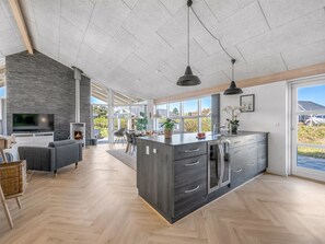 Eine moderne Küche mit einer großen Kochinsel, integrierten Geräten und einem Essbereich mit Sofa und Tisch.