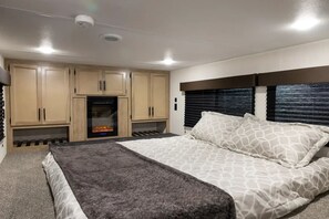 A bedroom with a bed, a fireplace, and wooden cabinets.