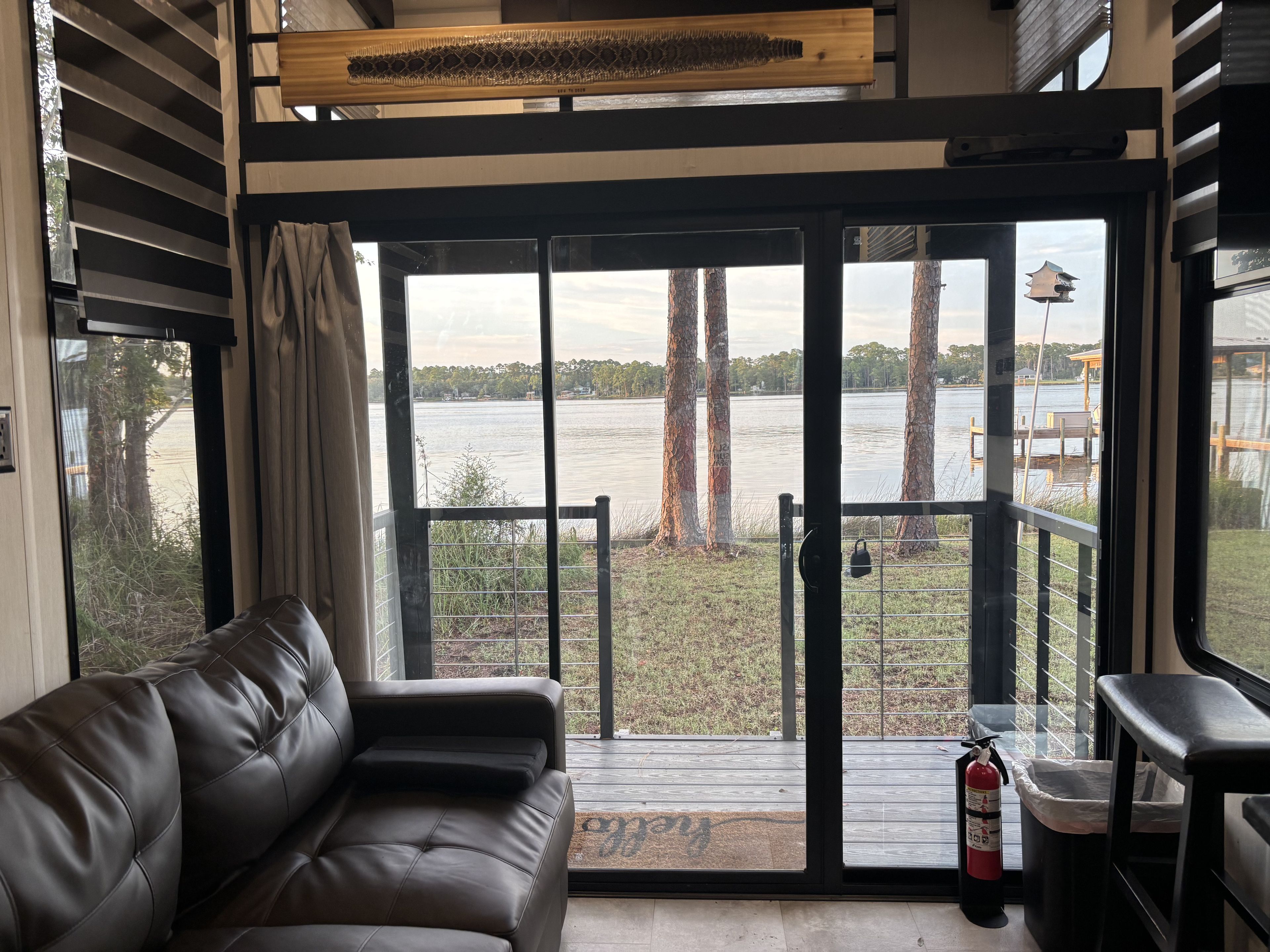 A room with a leather sofa, a sliding glass door leading to a deck, and a fire extinguisher.