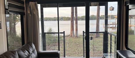 A room with a leather sofa, a sliding glass door leading to a deck, and a fire extinguisher.