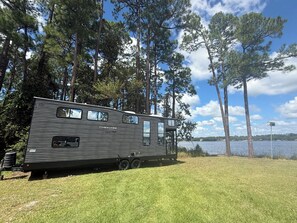 A motorhome parked in a grassy area with a lake and trees in the background.