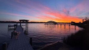 A pier extending into calm water with a sunset in the background.
