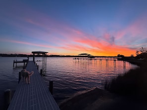 A pier extending into calm water with a sunset in the background.