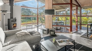 A modern interior with a fireplace, seating, and large windows offering views of the outdoors.