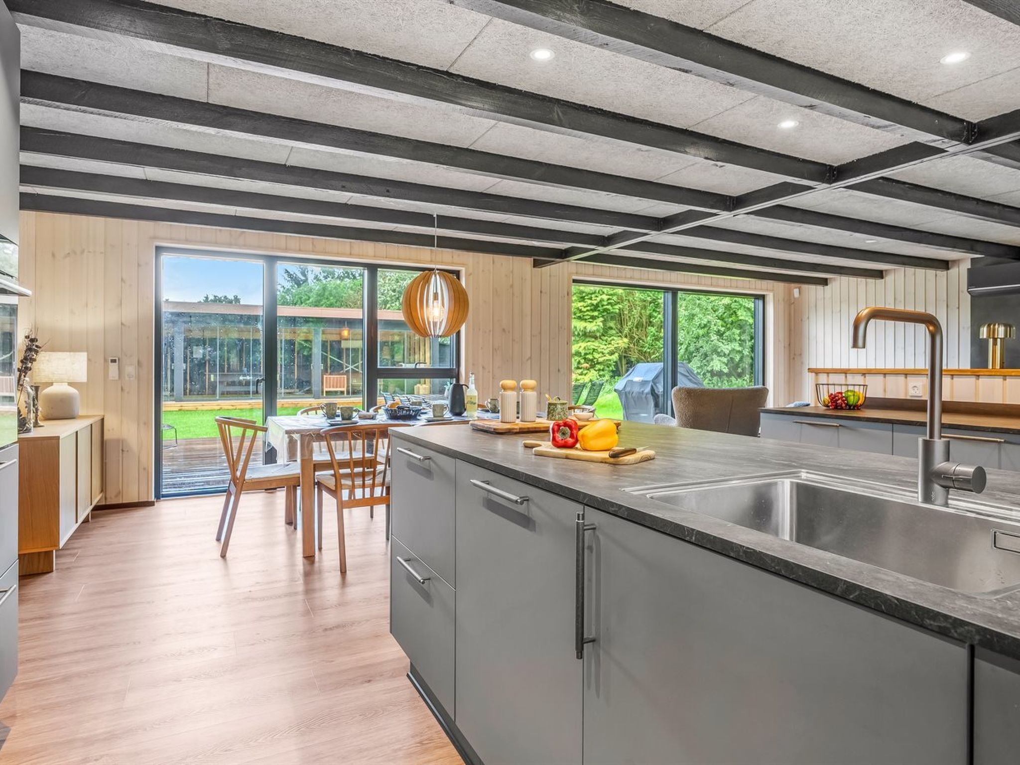 A modern kitchen with a large island, stainless steel appliances, and a view of the outdoors.