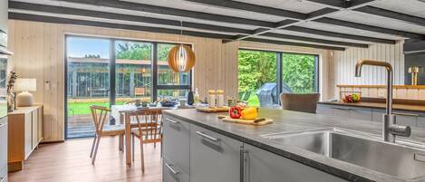 A modern kitchen with a large island, stainless steel appliances, and a view of the outdoors.
