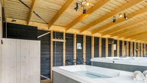 Ein Wellnessraum mit Holzbalken, einer großen Badewanne und einer Duschkabine.