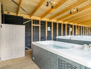 Ein Wellnessraum mit Holzbalken, einer großen Badewanne und einer Duschkabine.