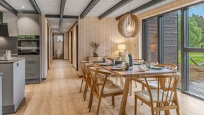 Eine moderne Küche mit Essbereich, Holzboden und großen Fenstern.