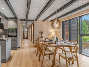 Eine moderne Küche mit Essbereich, Holzboden und großen Fenstern.