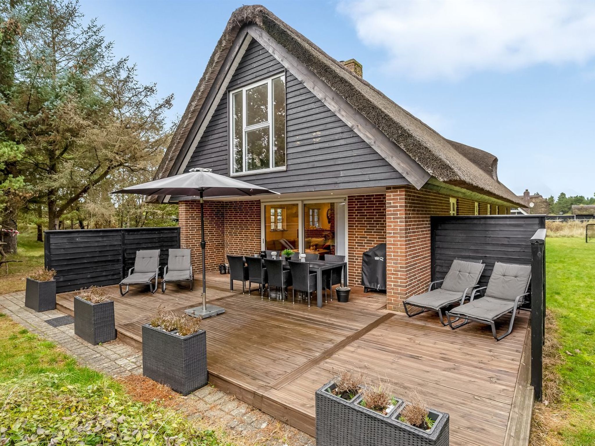 A house with a sloped roof, a patio with outdoor furniture, and a brick exterior.