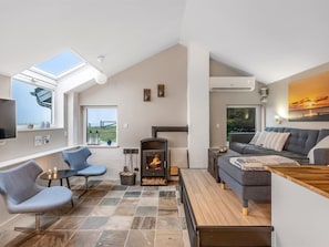 Ein modernes Wohnzimmer mit Kamin, einer Couch, einem Sessel und einem Fernseher.