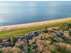 Ein Luftbild eines Küsteneigentums mit Strand, einem kleinen Haus und einem Boot.