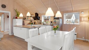 Una cocina moderna con armarios de madera, una isla central, iluminación colgante y vistas al exterior.