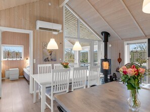 Una cocina moderna con muebles blancos, estufa de leña y comedor con vistas.