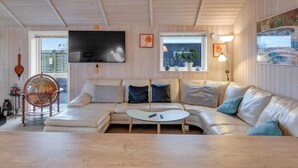 Una sala de estar acogedora con un sofá, una mesa de centro, un televisor y techo de madera.