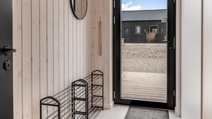 Un intérieur en bois avec une porte noire donnant sur un espace extérieur.