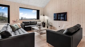 Un salon moderne doté d’une grande fenêtre, d’un téléviseur à écran plat et d’un décor intérieur en bois.