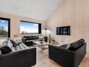 Ein modernes Wohnzimmer mit großem Fenster, Flachbildfernseher und Holzvertäfelung.