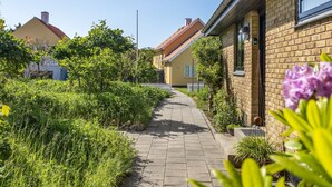En bostadsgata med hus, en asfalterad gångväg och grönska.