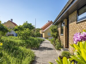 Eine Wohnstraße mit Häusern, einem gepflasterten Gehweg und Grünflächen.