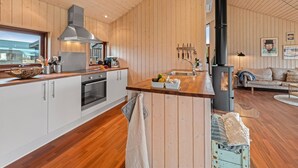 Una cocina moderna con paredes de madera, una estufa grande y un comedor con sofá.