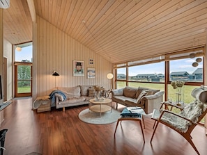 A spacious living room with wooden walls, a large window, a sofa, a coffee table, and a chair. - "Tamara" - 800m to the fjord by Interhome (Tarm)