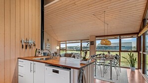 Una cocina moderna con armarios de madera, lavavajillas y comedor con mesa y sillas.