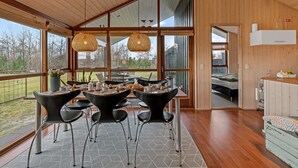 Un interior moderno con comedor que incluye mesa, sillas, ventanas amplias y vistas al exterior.