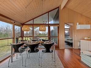 A modern interior with a dining area featuring a table and chairs, large windows, and a view of the outdoors. - "Tamara" - 800m to the fjord by Interhome (Tarm)