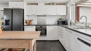 Ett modernt kök med vita skåp, ett svart kylskåp, en mikrovågsugn och en diskmaskin.