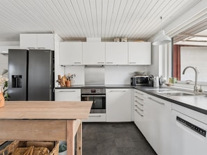 Eine moderne Küche mit weißen Schränken, einem schwarzen Kühlschrank, einer Mikrowelle und einem Geschirrspüler.