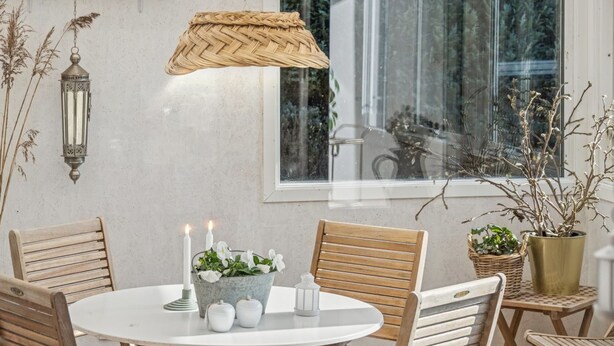 En matplats med ett runt bord, stolar, en hängande lampa och ett fönster med utsikt över träd.